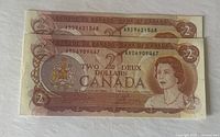 Front side of two 1974 Canadian $2 bills showing different serial numbers, both in clear and good condition.