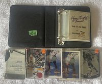 Photo showing binder with five cards visible inside plastic sleeves on a white surface. Cards include hockey and golf-themed Wayne Gretzky cards.