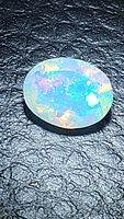 Oval cabochon opal on black textured background
