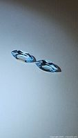 Pair of natural sky blue topaz marquis cut gemstones placed on flat surface showing color, shape and clarity.