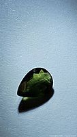 Pear-shaped green sapphire on white background