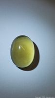 Oval natural lemon citrine cabochon gemstone under natural light showing color, size, and clarity.