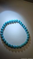 Close-up photo of natural turquoise bead bracelet showing polished round robin's egg blue beads with some matrix patterns.