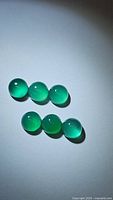 Six round vivid green onyx cabochons arranged in two rows on white background