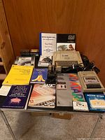 Atari 400 main unit, program recorder, joystick, various manuals, books, cartridges, and cassettes arranged on table.