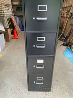 Front view of the black 4 drawer metal file cabinet showing handles, label holders, and non-locking drawers.
