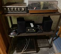Photo showing multiple audio components on metal shelves including two turntables, a Kenwood amplifier, Sony Hi-Fi system with speakers, and cable packaging.
