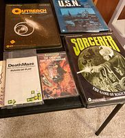 Photo showing Outreach, U.S.N., Sorcerer, The Creature That Ate Sheboygan, and Death Maze game boxes and rulebook, displaying vintage board games from SPI with sci-fi, fantasy and historical themes.