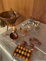 Full view of table display with assorted wooden and folk art decor items including carved animals, massage tools, and wooden abacus-like object.