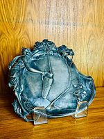 Full view front of the pewter tray showing detailed embossed maiden figure holding water jug and grapevine design around edges.