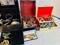 Wide view showing four main containers of costume jewelry including boxes and assorted pieces inside them