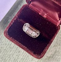 Ring displayed in a red velvet presentation box on green surface