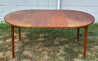 Full front view of oval teak table with leaves integrated on grass background