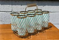 Set of 8 vintage tumbler tea glasses with teal swirl design and gold rims in gold metal caddy carrier.