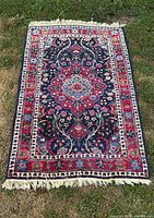Full view of rectangular hand-knotted wool rug laid on grass