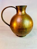 Full view of the vintage solid copper water pitcher showing round body and handle.