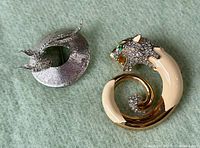 Photo showing both JOMAZ and Kenneth Jay Lane brooches on a green felt background.