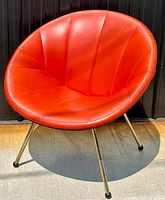 Front view of orange vinyl scoop chair showing channel tufting and brass-toned legs