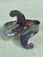 Close-up of the silver cuff bracelet with abstract wave ends showing the polished shiny surface and smooth curves