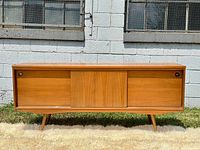 Front view of walnut sideboard with sliding doors and tapered legs outdoors