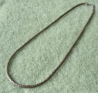 Full view of the vintage sterling silver Byzantine link necklace laid flat on a green felt surface.