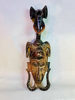 Full frontal view of the carved wooden Guro mask showing detailed human and animal features.