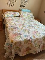 Front angled view of wooden bed frame with floral quilt and pillows, headboard visible with minor scratches.