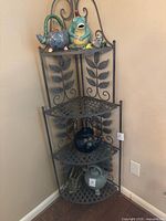 Full view of the foldable three tier corner metal stand with decorative leaf back panels and lattice shelves, showing details of design and craftsmanship.
