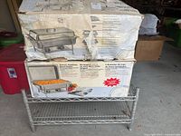 Worn box showing image and description of deluxe stainless steel chafing dish on metal stand.