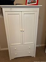 Front view of white wooden Graco entertainment center with two cabinet doors and two drawers below, showing overall condition and details.