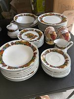 Overview of all pieces showing stack of plates, bowls, sugar bowl, creamer, and turkey salt and pepper shakers