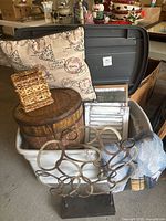 Lot with printed pillow, metal circular-loop sculpture, wooden basket, woven tissue holder, nautical throw, and tote bag in a white plastic bin