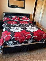 Bedframe and headboard set with bedding laid on queen mattress, red and white floral pattern visible