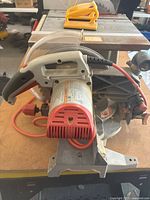 Front and side view of the Ridgid 10-inch compound miter saw showing the motor, orange power cord, and blade guard.