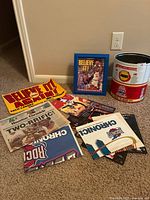 Photo showing various Rockets memorabilia laid out on carpet, including a rusted metal trash can, framed player photo, newspapers, and posters.