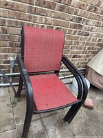 Side and front view of four stacked red metal frame patio chairs, showing weathered red fabric seats and backs.