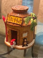Front angle showing tiki hut dispenser with Tiki Hut sign, monkey figure, and red spigot