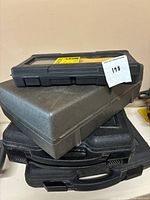 Stacked black and gray tool cases seen from above on a table.