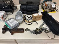 Overview of lot on countertop showing all items spread out including lamp, battery box, winch, hitch, cords, and tool cases
