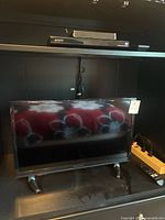 Photo of 23-inch Insignia smart TV with stand on dark furniture, power strip nearby.