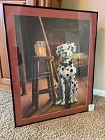 Full shot of framed print showing the Dalmatian dog, wooden stool with beer mug, and overall composition within a black frame, placed on carpet against a light-colored wall.