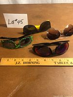 Group shot of four pairs sunglasses with ruler for scale