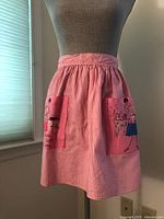 Full view of pink gingham half apron on mannequin