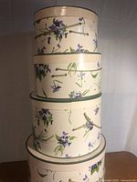 Stacked view of all four nesting hat boxes showing floral pattern and rope handles