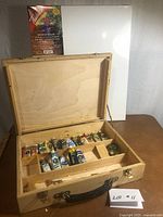 Closed wooden paint box beside wrapped canvas board