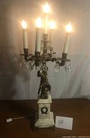 Full view of five-light marble and brass cherub lamp illuminated