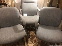 Three matching grey upholstered chairs, two sled-base and one office on wheels