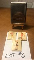 Front view of cigarette case standing, three matchbooks laid out