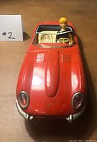Front view of red tin Jaguar toy car with driver