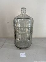 Front view of 6 gallon glass carboy showing embossed grid design and narrow neck